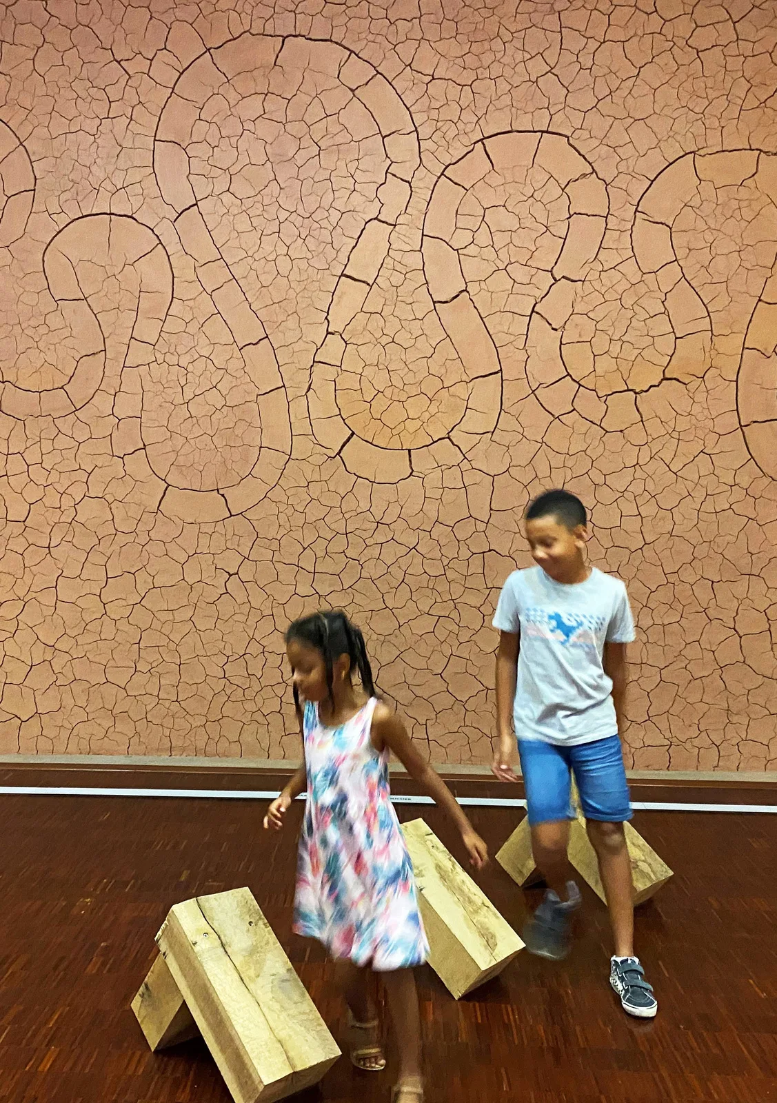 Deux enfants s'amusent au musée Gassendi dans la salle des paysages devant l'oeuvre d'Andy Goldsworthy