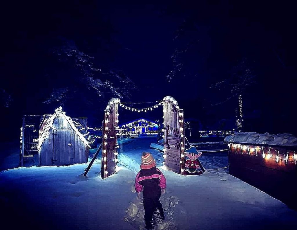 Petite fille qui marche dans la neige au village de Noël