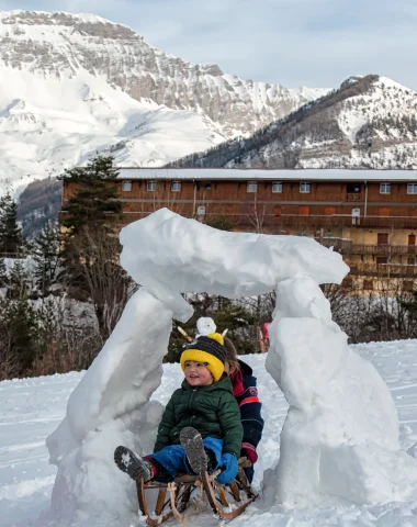 Child sledding under a snow arch at the Grand Puy resort