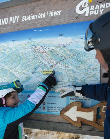 Famille qui regarde le plan des pistes de la station du Grand-Puy
