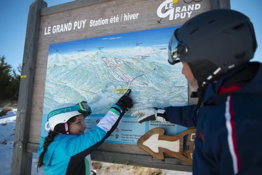 Famille qui regarde le plan des pistes de la station du Grand-Puy